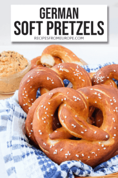 Photo of brown soft pretzels with salt on blue and white dishtowel with cheese spread in background and text overlay saying German soft pretzels