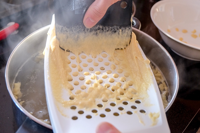 german egg noodle batter on white plastic spaetzle maker