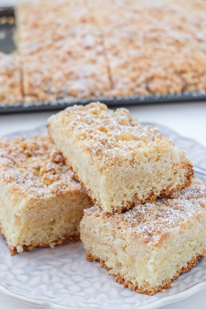 german crumb cake slices stacked on plate with crumb cake behind