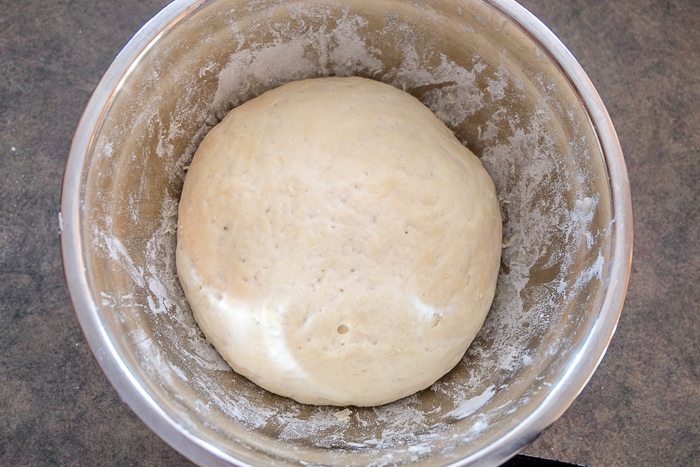 german bread roll dough risen in silver mixing bowl