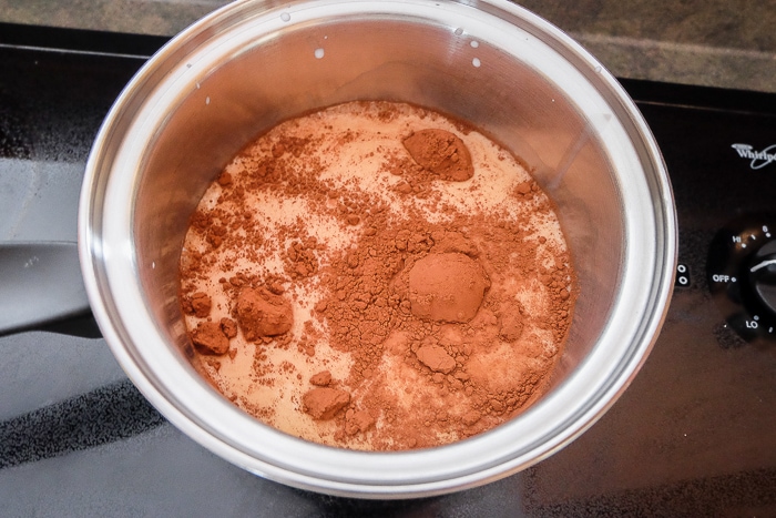 cocoa powder in milk in pot on stove top