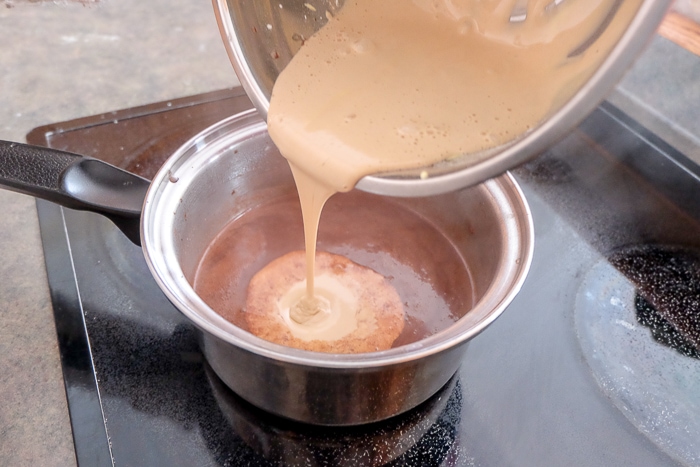 mixing corn starch mixture into chocolate milk mixture in pot on stove