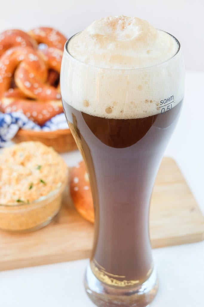 german colaweizen drink in tall beer glass with pretzels behind