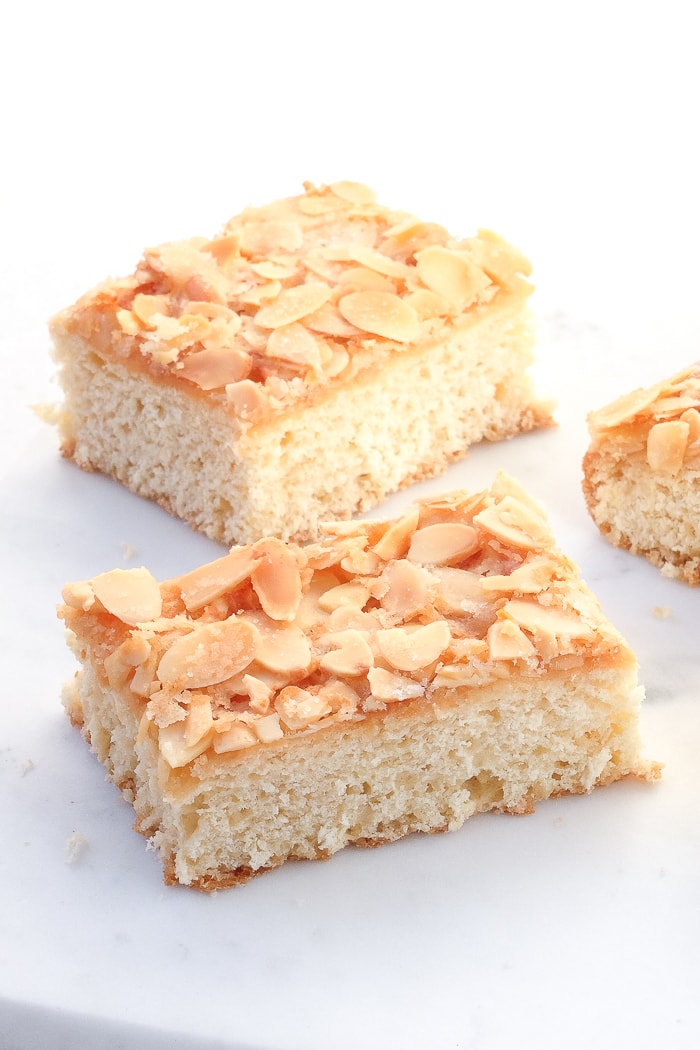 rectangle slices of butter cake with crispy almonds on top on white marble platter
