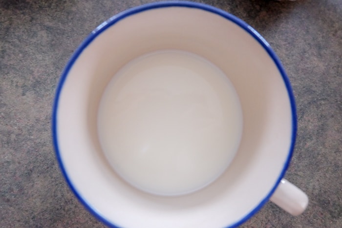 white mug on counter with milk inside