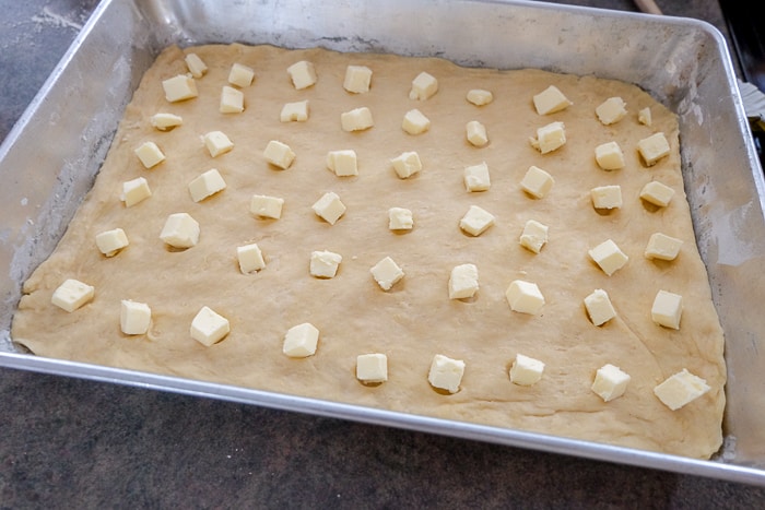 chunks of butter in raw german butter cake dough in baking pan
