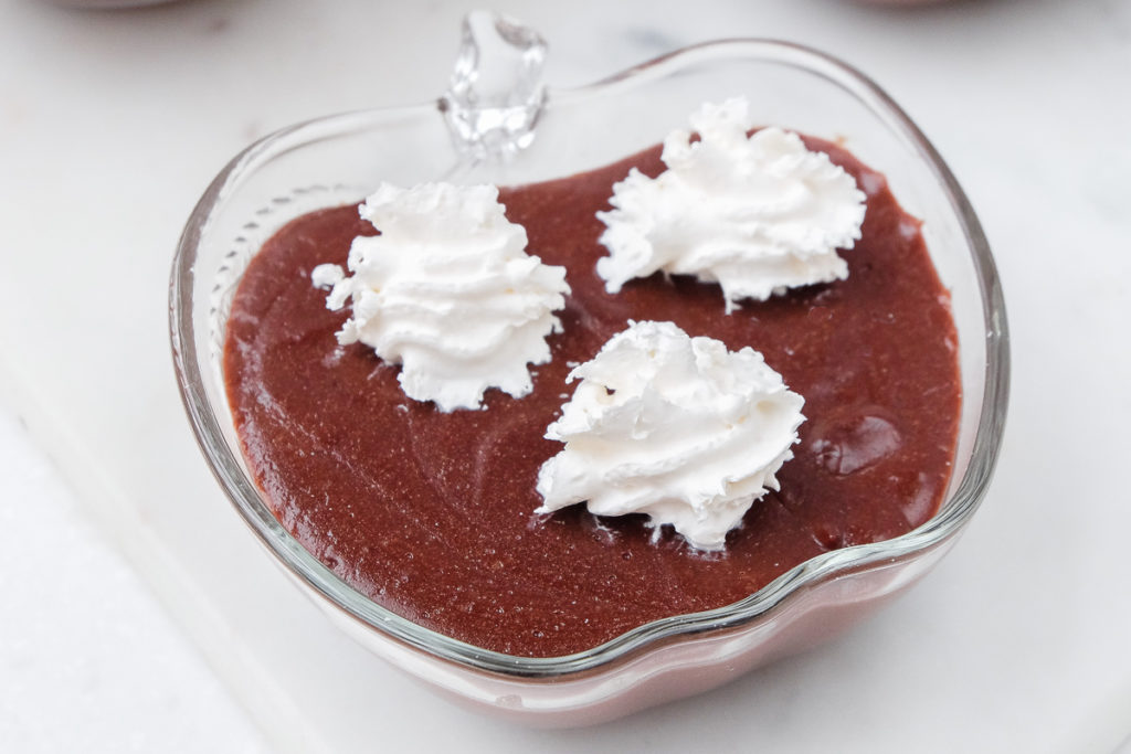 clear bowl of chocolate pudding with whipping cream on top