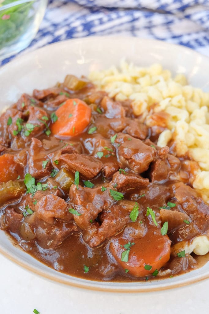 german goulash with beef and carrots in bowl with spaetzle noodles.