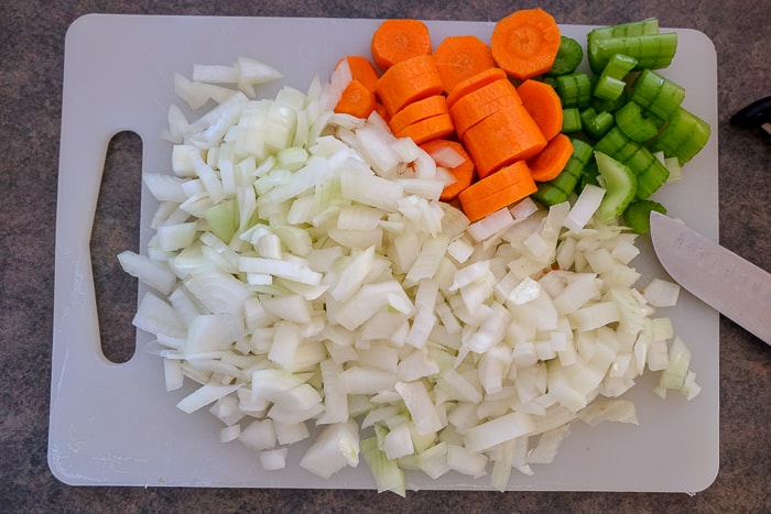 chopped carrots onions and celery on white cutting board