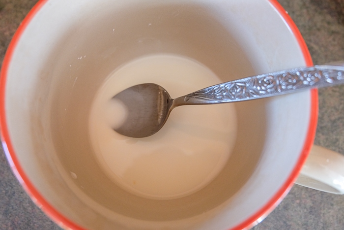 mug of corn starch with silver spoon stirring
