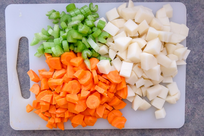 carrots potatoes and celery chopped on white cutting board