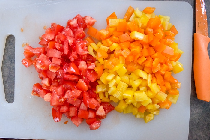 chopped red and orange peppers on white cutting board