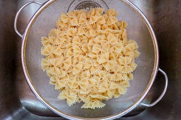 bowtie pasta cooked in metal strainer in sink