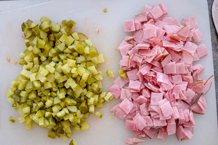 chopped pickles and ham on white cutting board