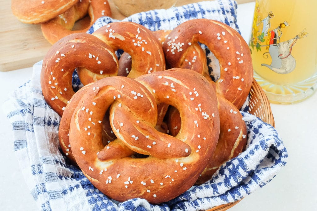 german pretzels in basket with blue cloth with radler beer mug beside