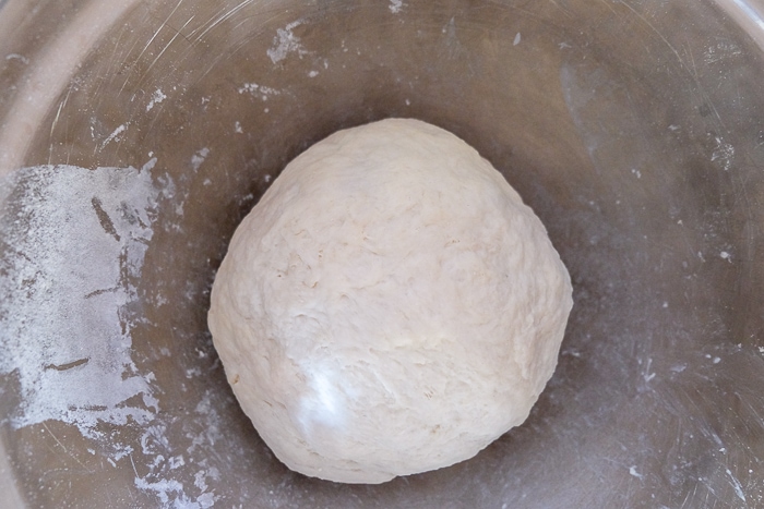 ball of pretzel dough in silver mixing bowl