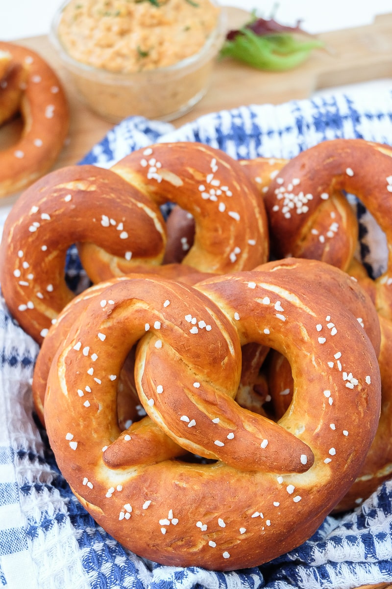 german pretzels in basket with orange obatzda cheese behind