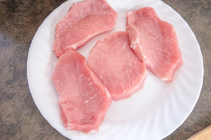 cuts of pink pork on white plate on counter