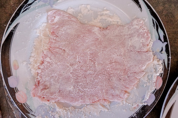 pork schnitzel on plate covered in flour