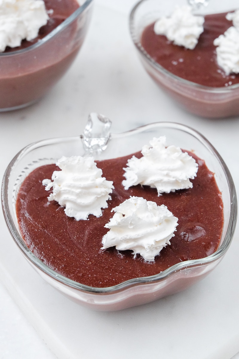 glass bowls of homemade chocolate pudding with dots of whipping cream on top