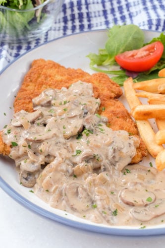 jagerschnitzel german recipe german jagerschnitzel on plate with mushroom sauce on top and fries beside
