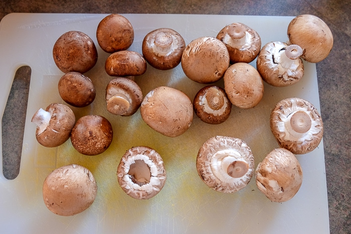 whole clean mushrooms on white cutting board on counter