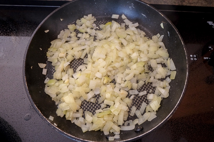 cooking onions in black frying pan on stove