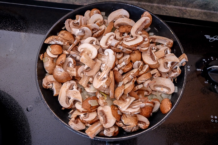 mushrooms cooking in black frying pan on stove
