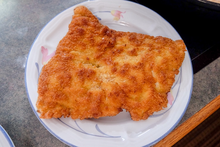 golden brown schnitzel on white plate on counter