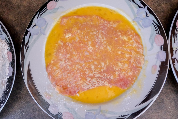 pork schnitzel on plate coated in raw egg