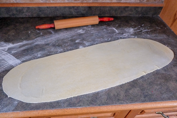 german stuffed pasta dough rolled thin on counter with rolling pin behind