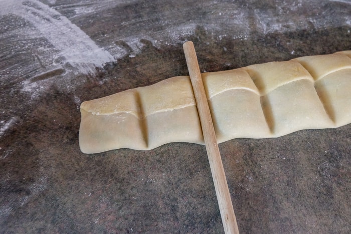 maultaschen pasta pockets with wooden spoon pressing down on the dough
