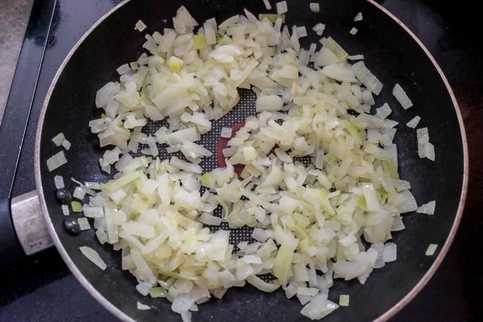 chopped onion sautéing in black frying pan 