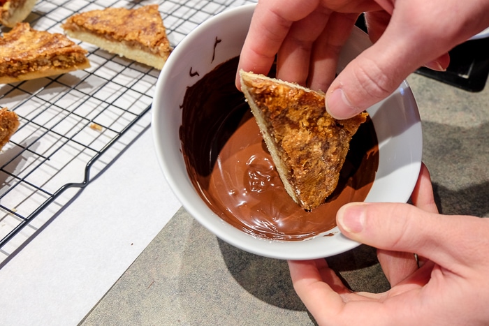 nussecken bar in hand dipping in bowl of melted chocolate
