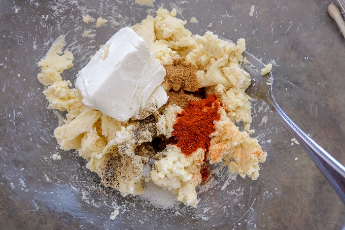 cream cheese and spices in bowl with fork mixing ingredients