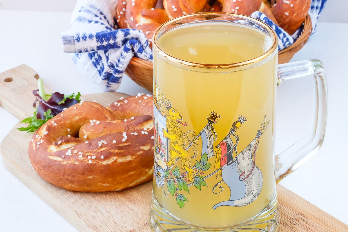 german glass mug with radler beer beside pretzels on wooden board