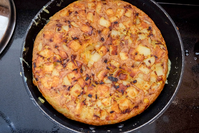 flipped spanish omelette in black frying pan on stove top