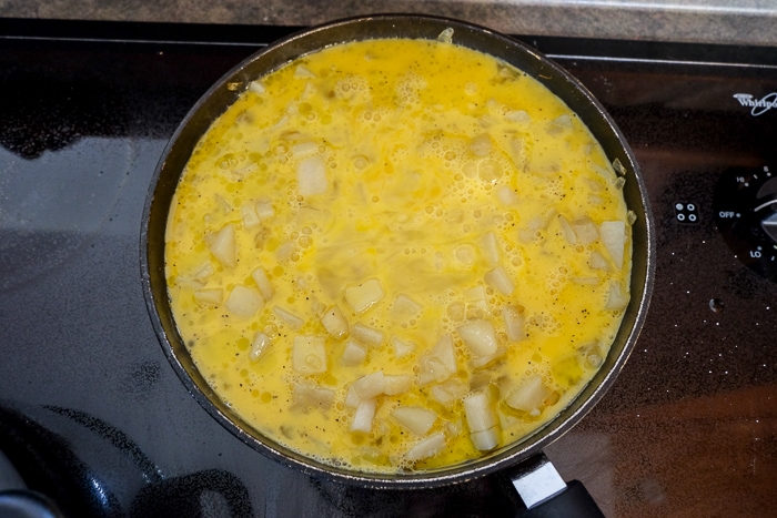 eggs and potatoes of spanish tortilla in frying pan on stove