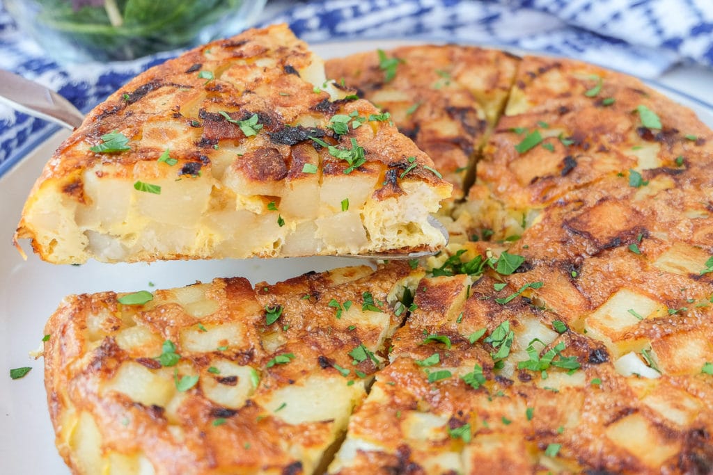 spanish omelette with egg and potato cut into slices with parsley on top