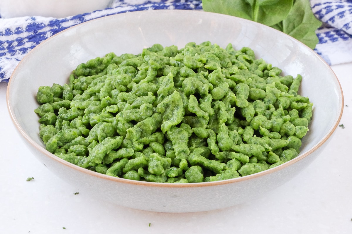 bowl of green spinach spaetzle on white counter top