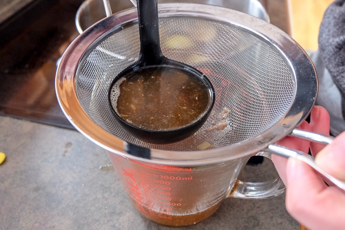 beef broth spooned through strainer into cup below