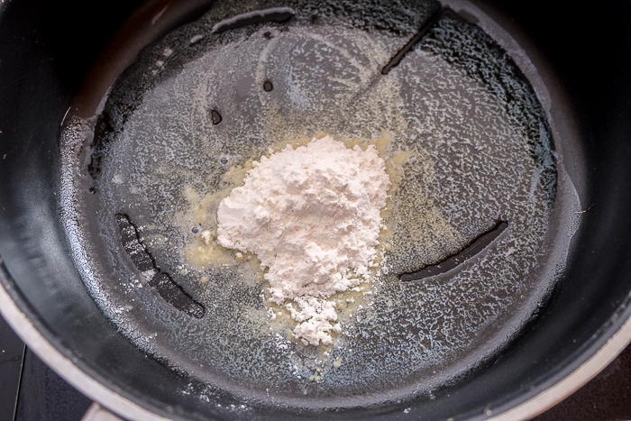 flour sitting in melted butter in large black sauce pan