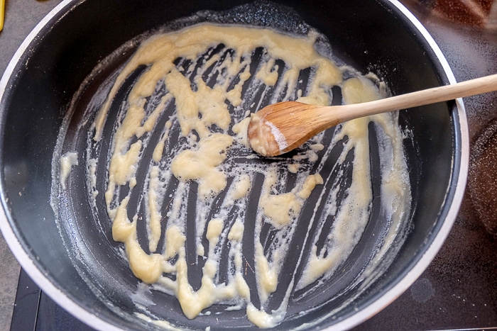 flour and butter in sauce pan mixing with wooden spoon