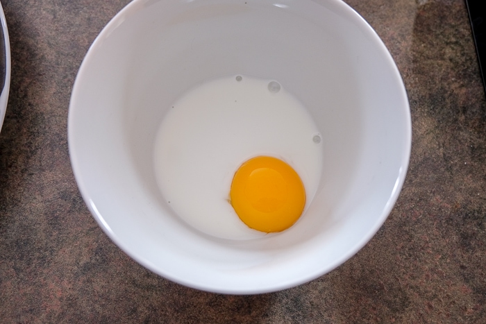 egg yolk in white bowl with milk on counter