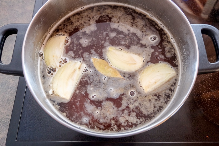 onions and bay leaf floating in pot of beef broth