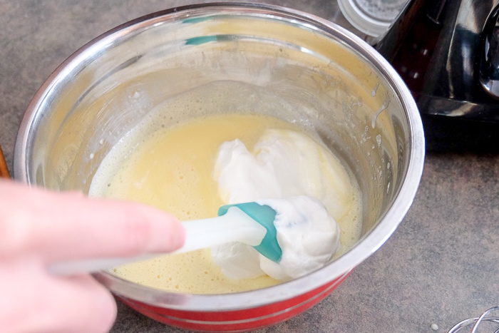 whipping cream folding into bowl with green spatula