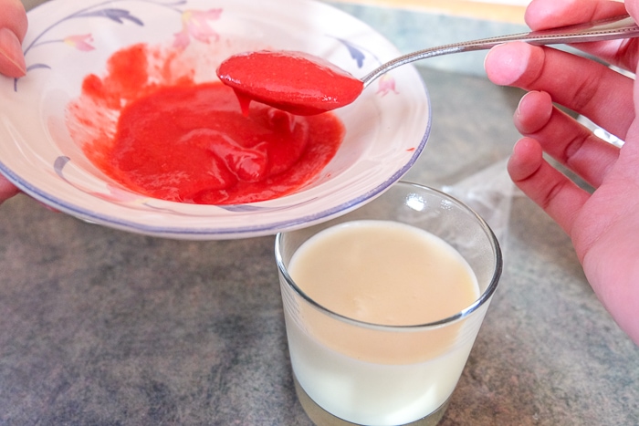 spooning raspberry puree onto bavarian cream in glasses