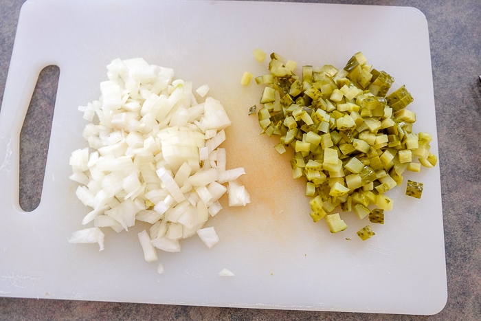 chopped onions and pickles on white cutting board