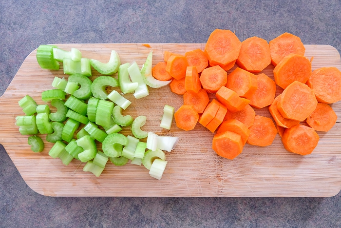 sliced carrots and celery on wooden cutting board on counter
