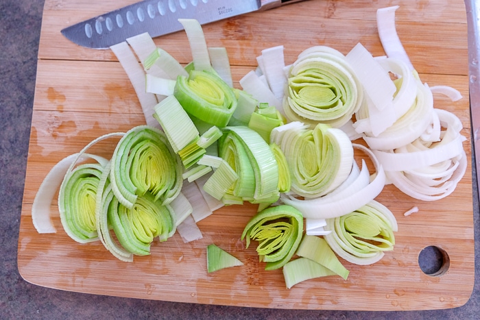 chopped leek on wooden cutting board with knife